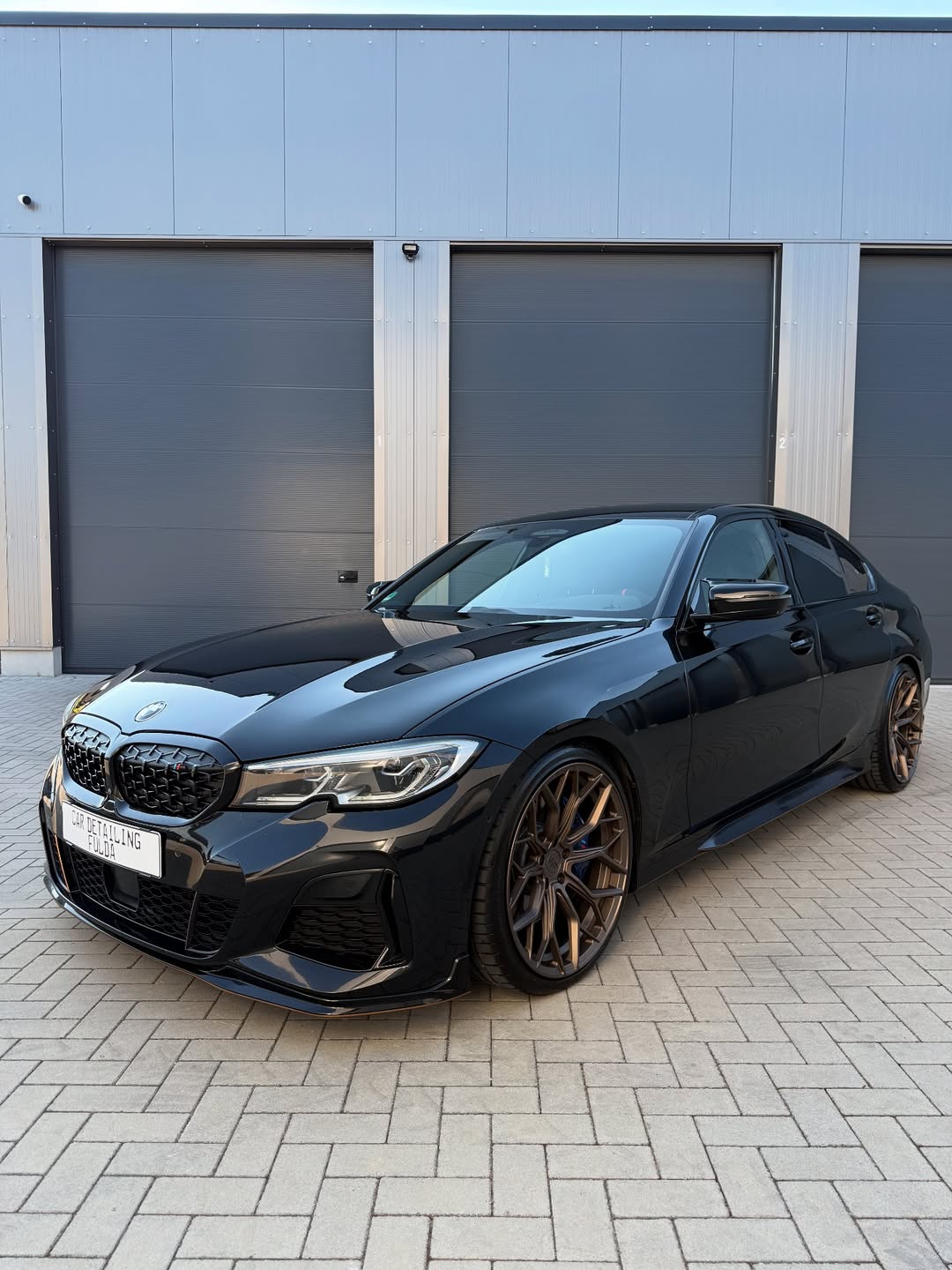 BMW M340i mit glänzendem schwarzen Lack und bronzefarbenen Felgen nach Fahrzeugaufbereitung bei Car Detailing Fulda.